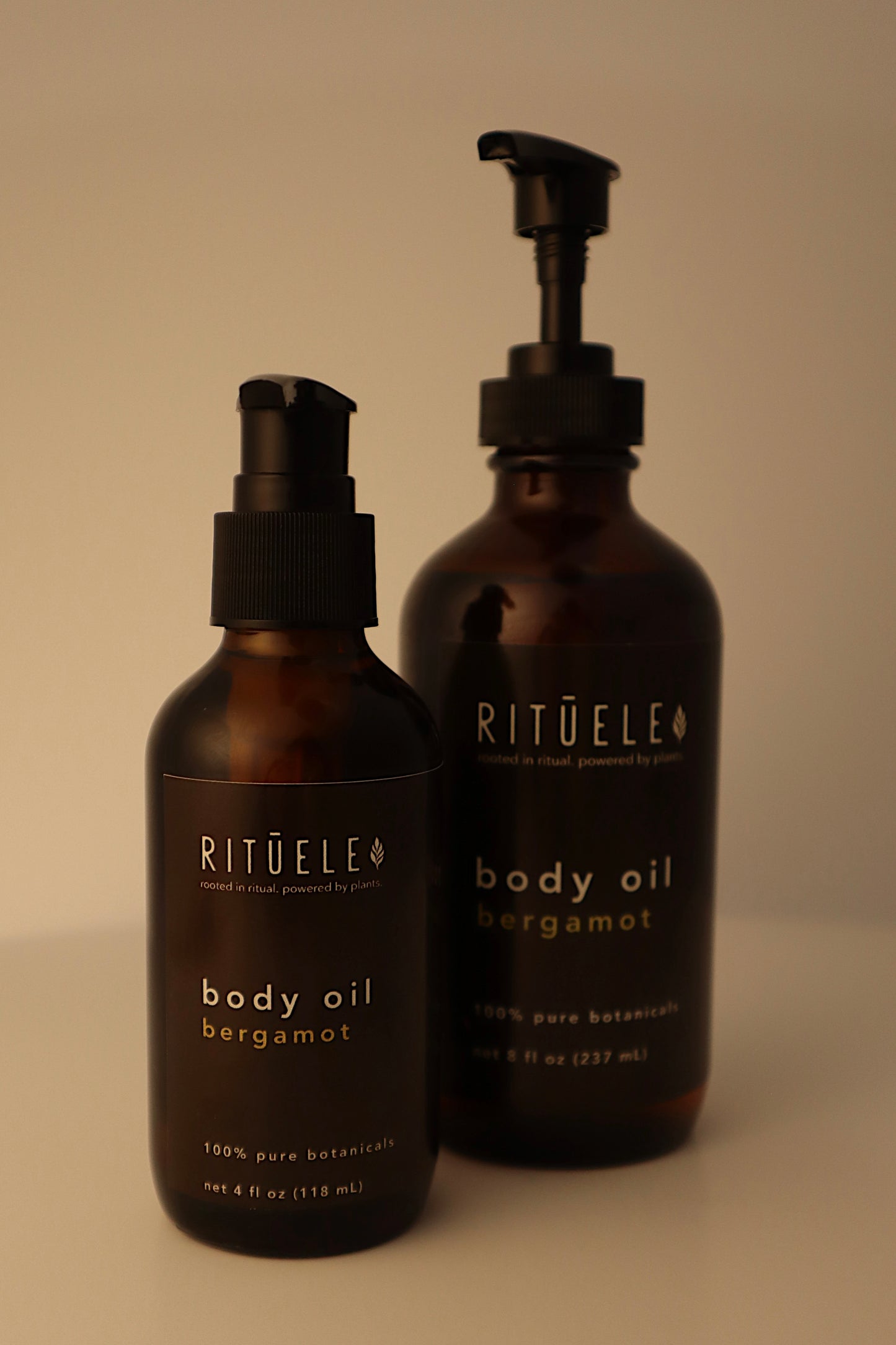 Two bottles of RITUELE body oil on a beige background
