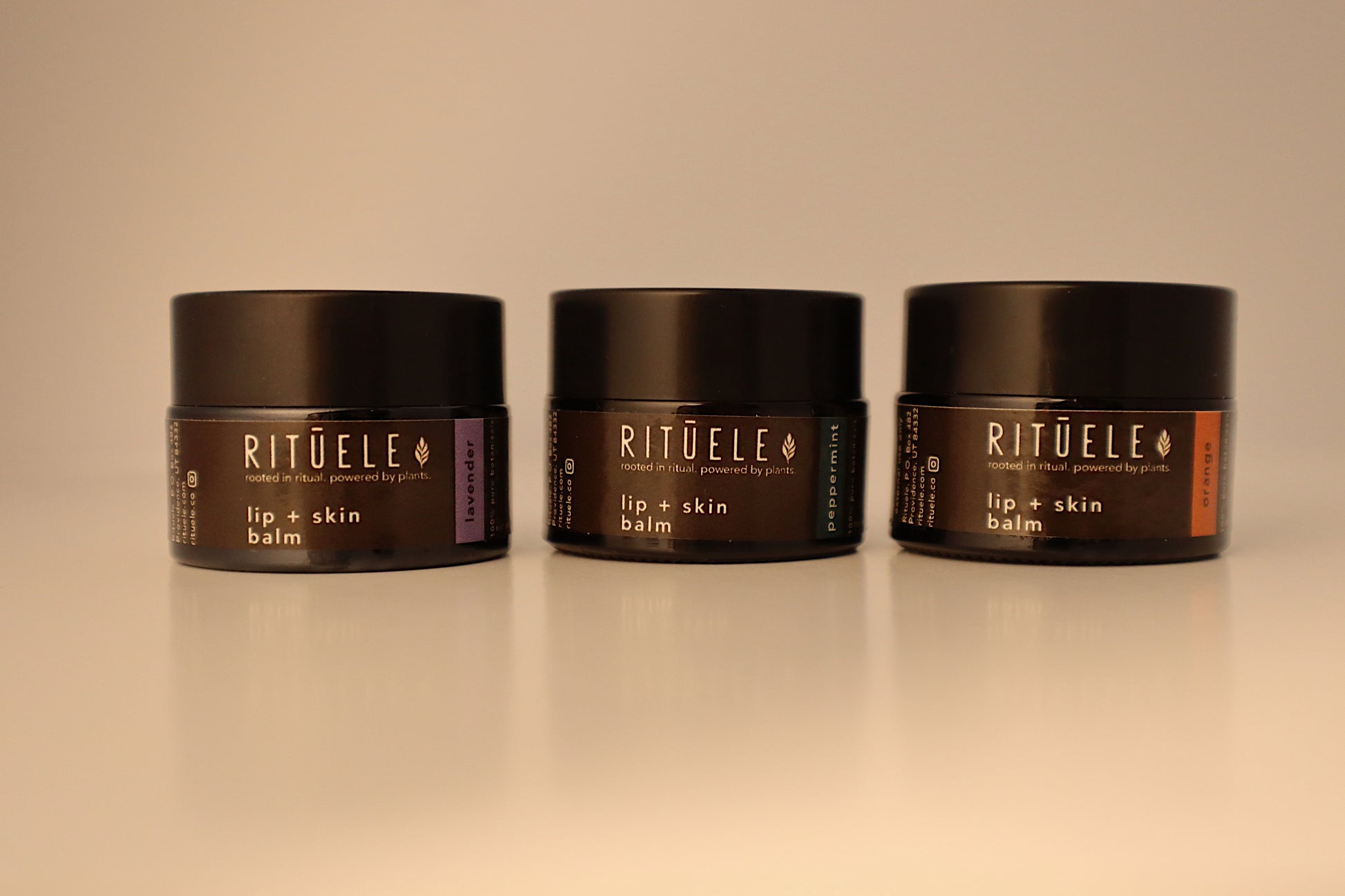 Three jars of RITUELE lip and skin balm on a beige background