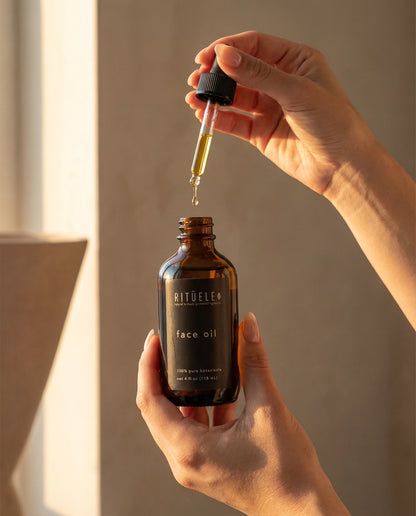 Rituele skincare face oil bottle with dropper held by a hand against a neutral background