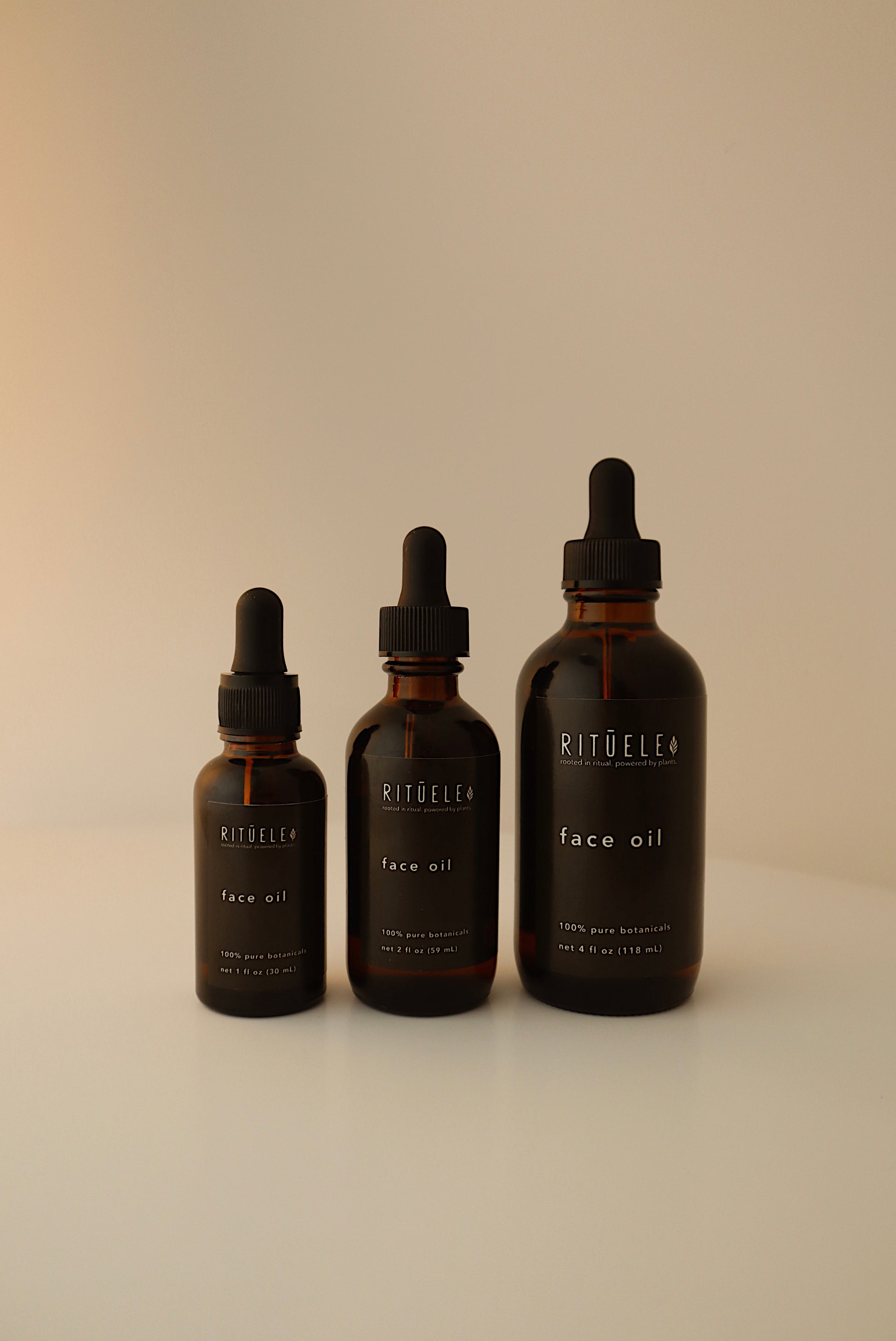 Three bottles of Ritualee face oil on a beige background