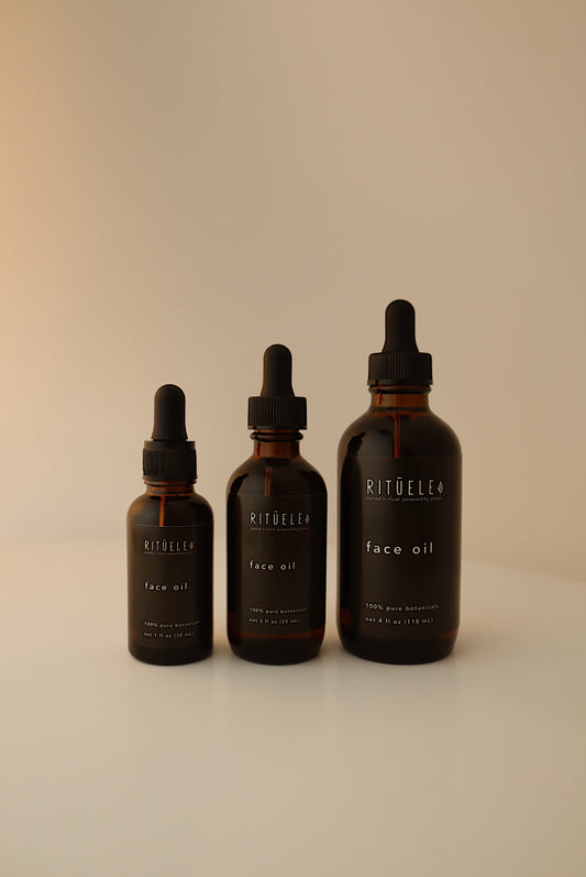 Three bottles of Ritualee face oil on a beige background